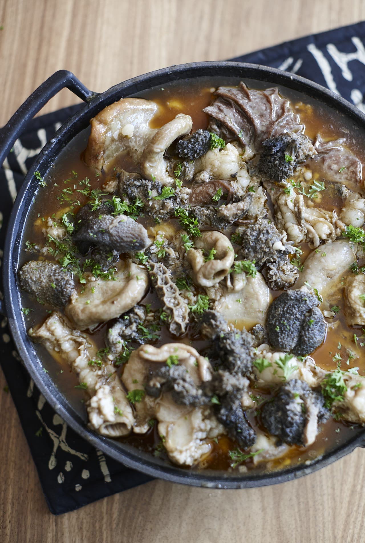 Cast iron pot of slow-cooked Mala Mogodu finished with fresh herbs